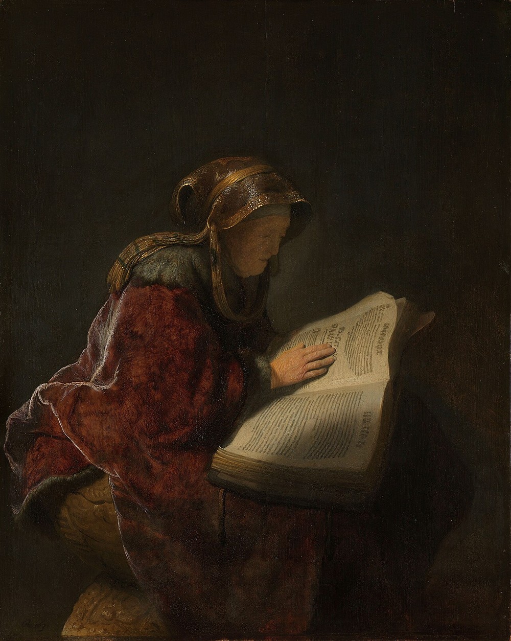 An elderly woman in a fur-trimmed cloak bent over a large open book on a stand, one hand resting flat on the lit page