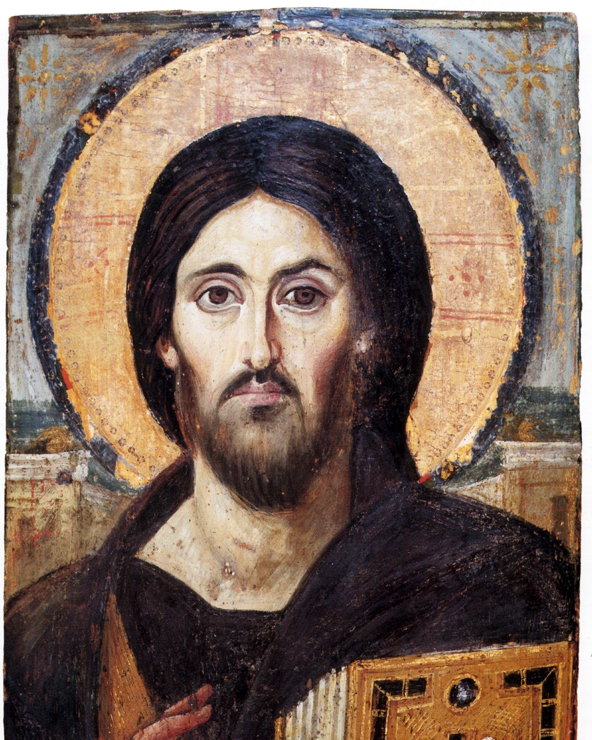 An ancient icon of Christ facing the viewer, with dark hair and beard, a golden halo, one hand raised in blessing and a jewelled book of the Gospels held in the other