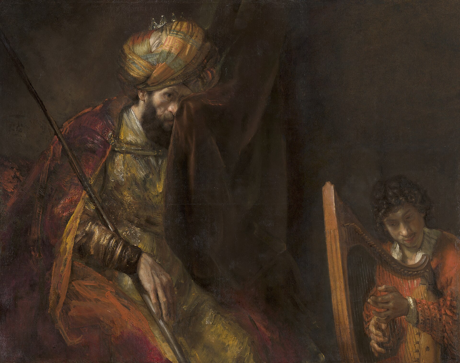 King Saul in a jewelled turban and crown, a spear in his hand, pressing a curtain to his weeping eye while the young David plays the harp beside him, in a painting by Rembrandt