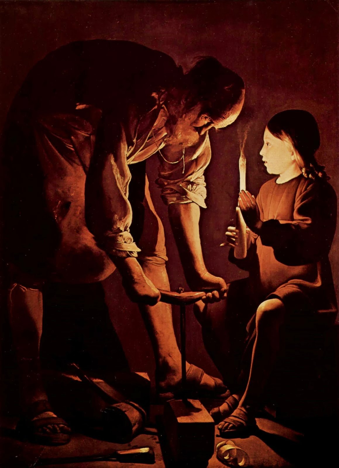 In a dark workshop an older man bends to bore a hole in a wooden beam while a young boy holds a candle for him, the flame lighting both their faces