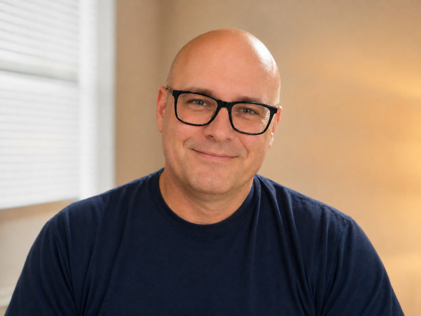 Douglas Vandergraph, smiling, wearing black-framed glasses and a navy T-shirt
