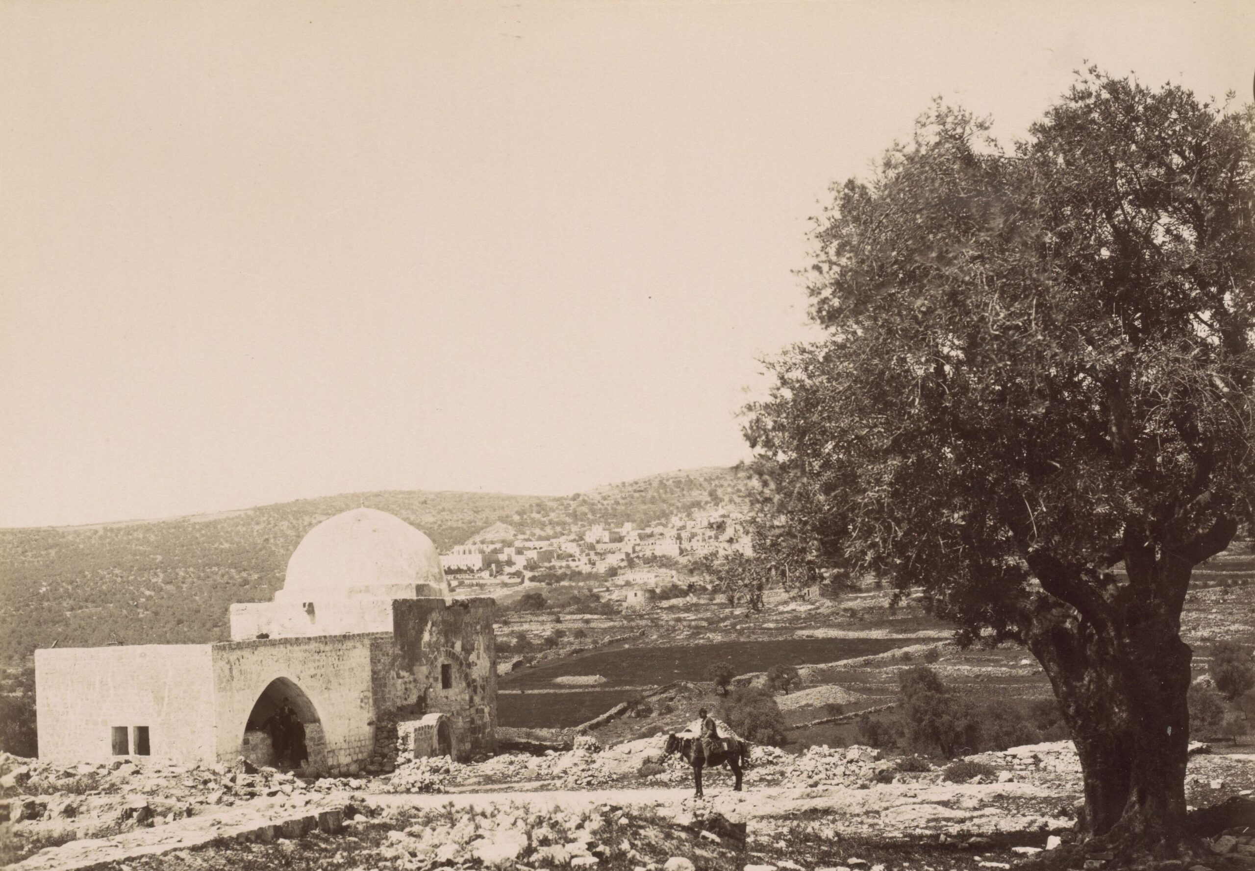 I Will Write It In Their Hearts 1 Old sepia photograph of Rachel's Tomb, a small domed stone building on a rocky hillside near Bethlehem, beside a large olive tree, with a man on a donkey on the road