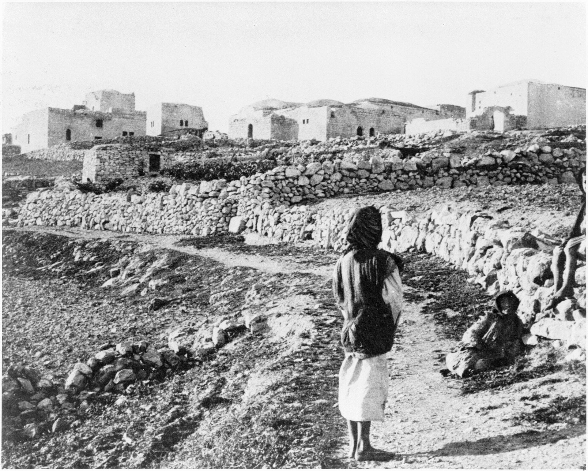 He Bought A Field At Anathoth 1 Old black-and-white photograph of the stone village of Anathoth on a hilltop, with terraced fields, low stone walls, and a boy walking on a dirt path